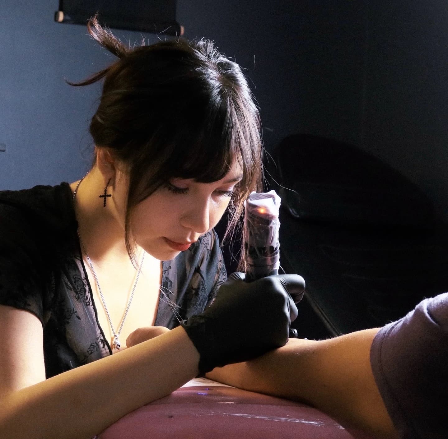 Javiera, tattoo artist at Cazagemas, focused on tattooing a forearm in the studio