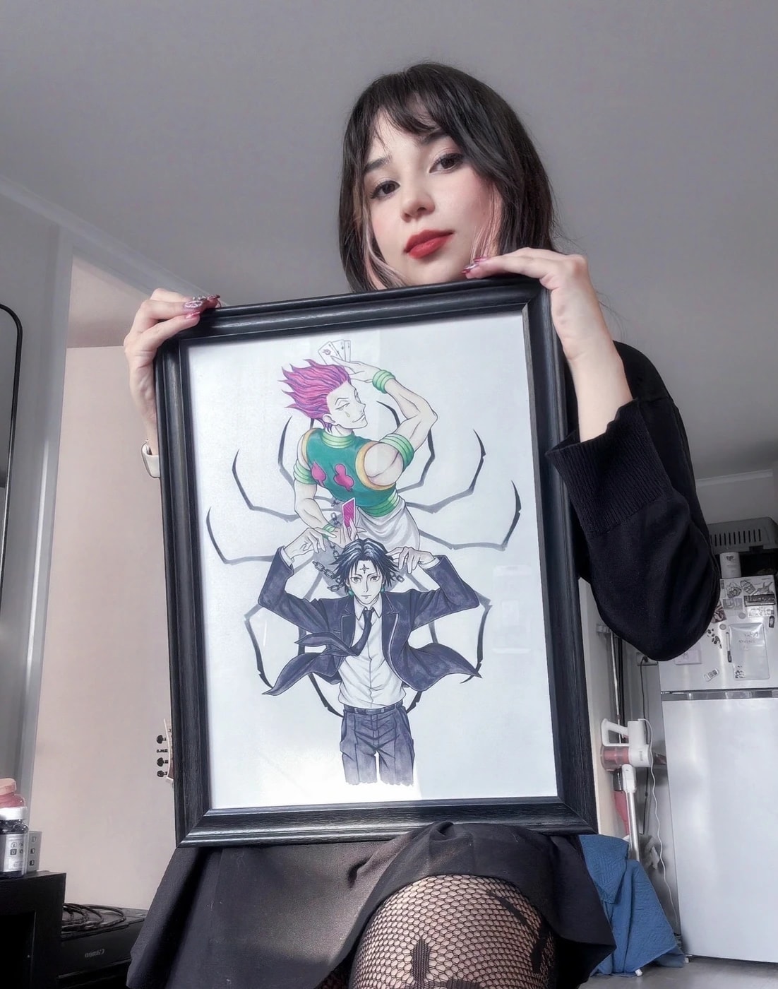 Javiera holding one of her framed illustrations of anime characters
